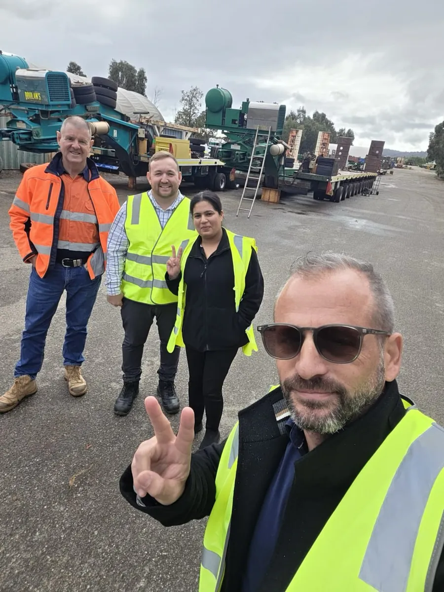 Paul Cohalan and the All Trucks Insurance team on site at an Australian trailer yard with heavy float trailers behind them